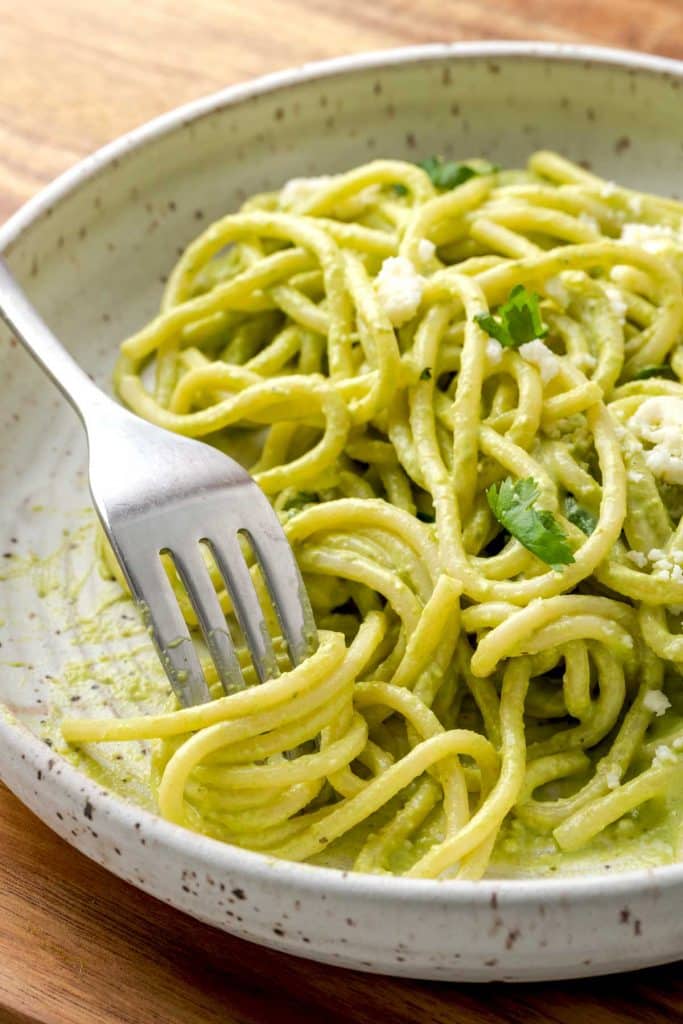 A fork twisting creamy pasta in poblano green sauce 