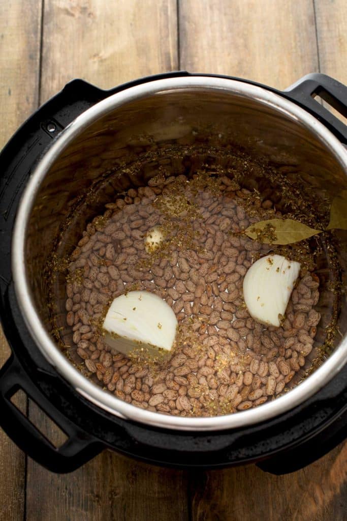 Instant Pot filled with ingredients to cook pinto beans.