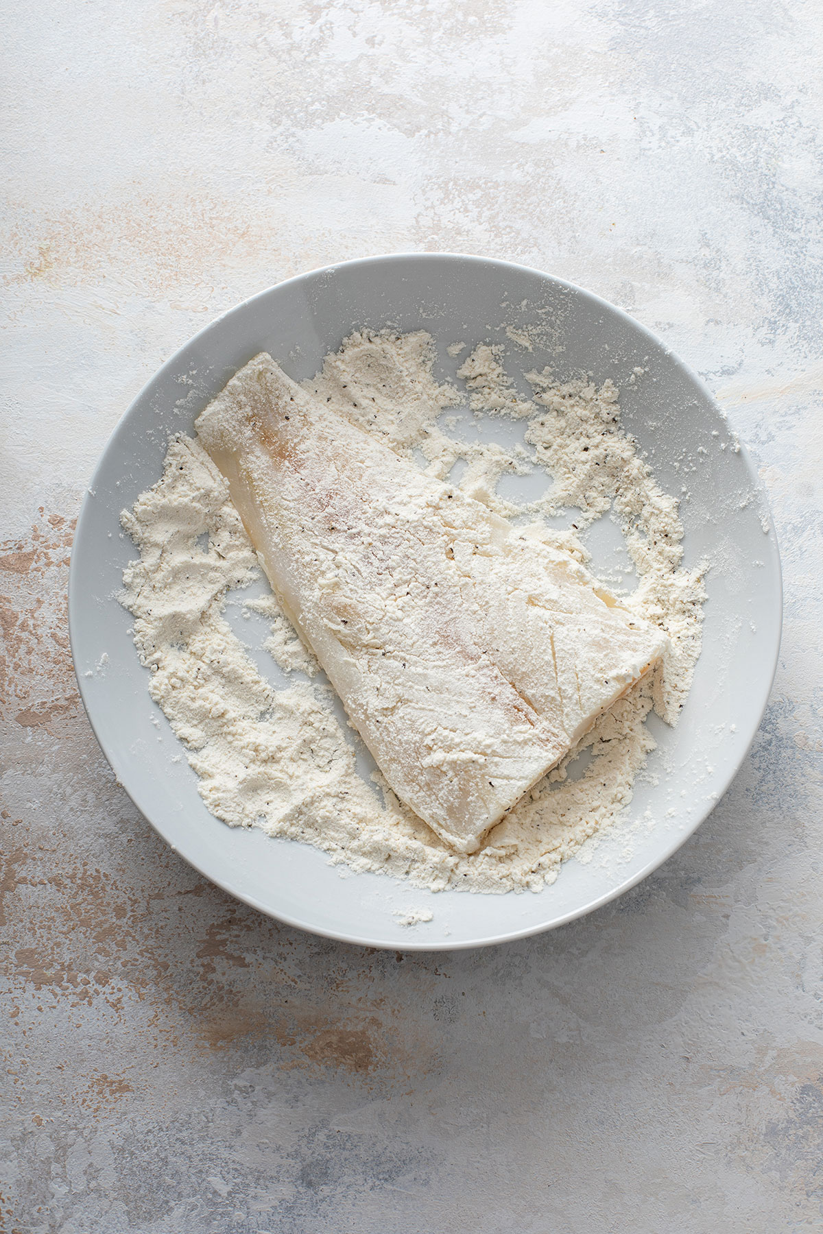 Cod fish fillets getting dredge in flour