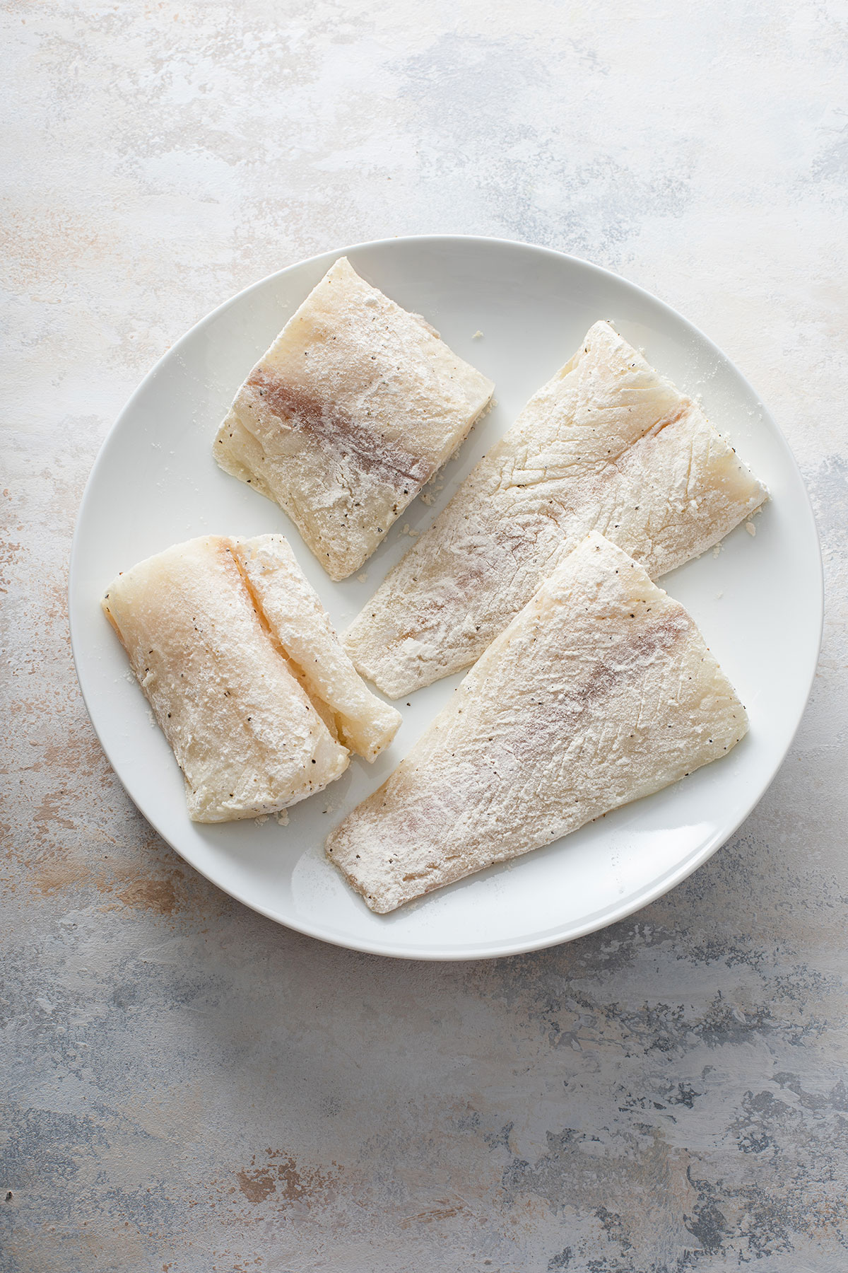 Flour coated cod fillets on a plate