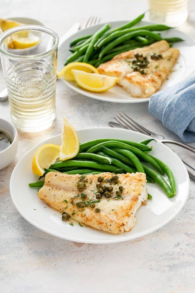 Golden brown seared cod fish smothered on lemon butter and served with green beans and lemon wedges.