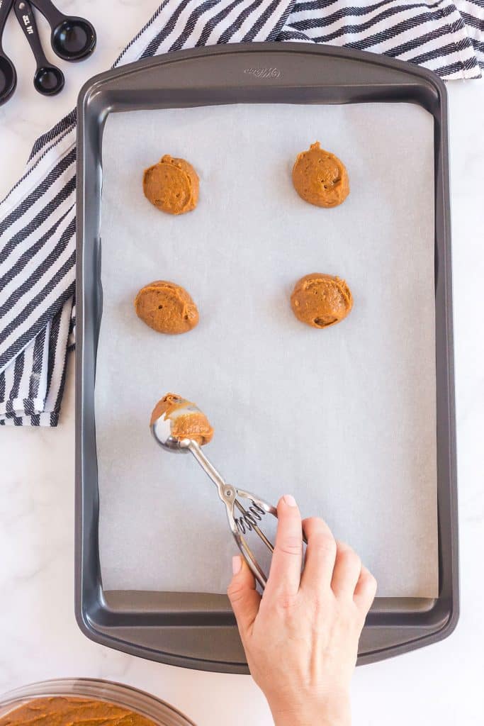 scooping whoopie pie batter in a baking sheet with parchment paper