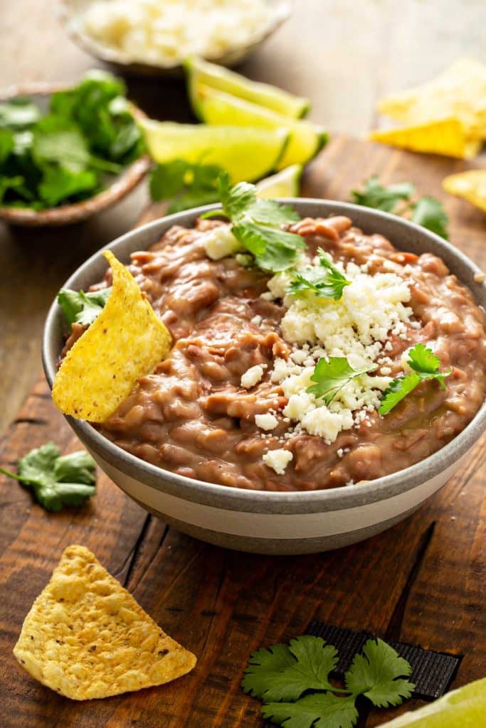 Authentic refried beans with crumbled queso fresco and chopped cilantro in a small bowl.
