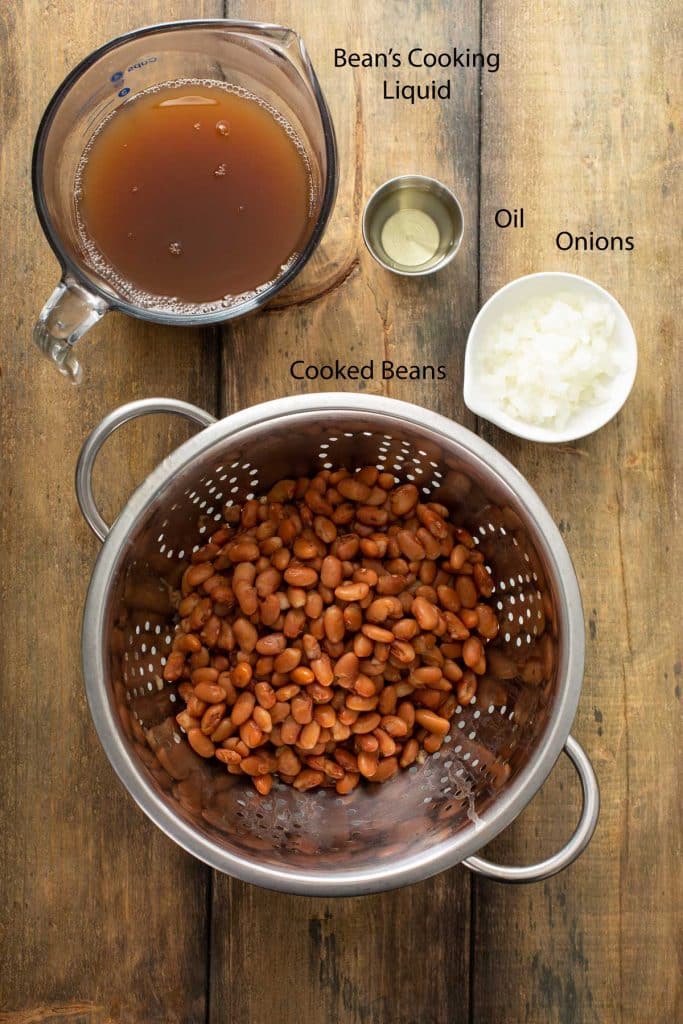 Ingredients to pan-fry Mexican refried beans. Cooked pinto beans, minced onions, the beans' cooking liquid and oil.