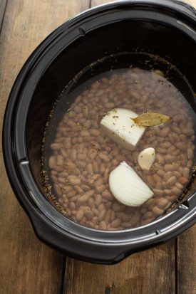 Crockpot filled with ingredients for refried beans.