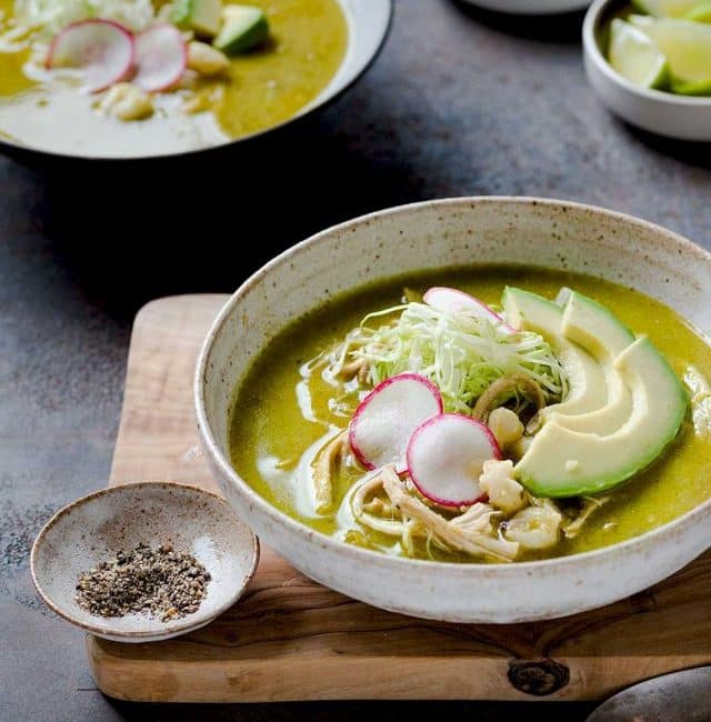 Bowl of pozole topped with avocado, radishes and cabbage
