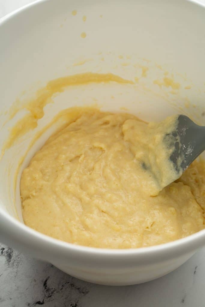 donut batter in a white bowl with a gray spatula
