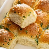 Soft and fluffy dinner rolls brushed with herb butter on a baking dish