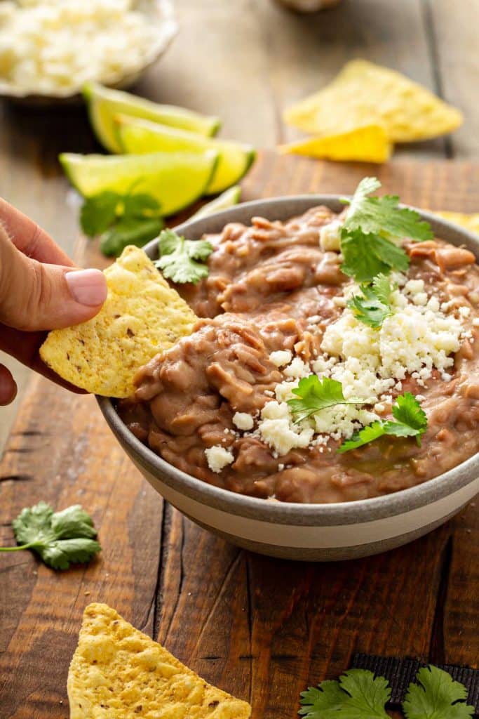 Scooping creamy refried beans with a tortilla chip.