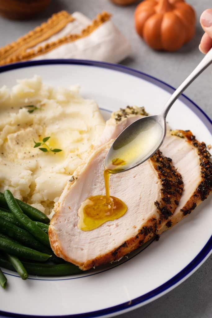 Pan juices are drizzled over slices of turkey breast