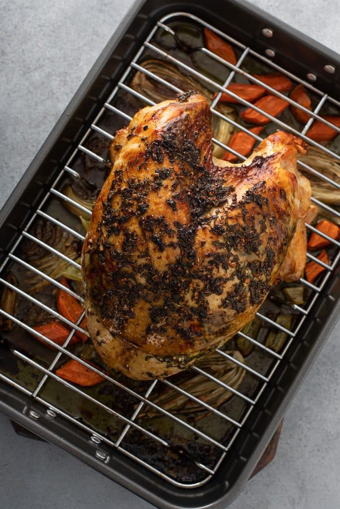 Golden brown whole turkey breast on a rack inside a roasting pan.
