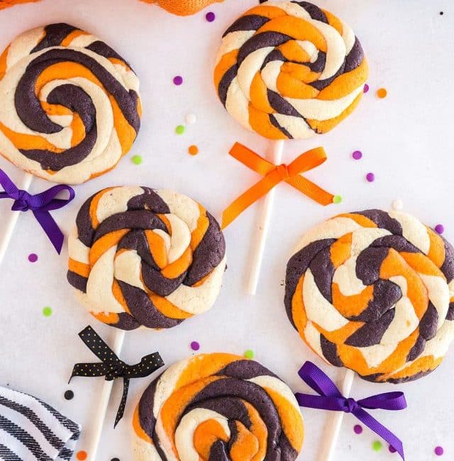 five halloween lollipop cookies with bows on a white surface