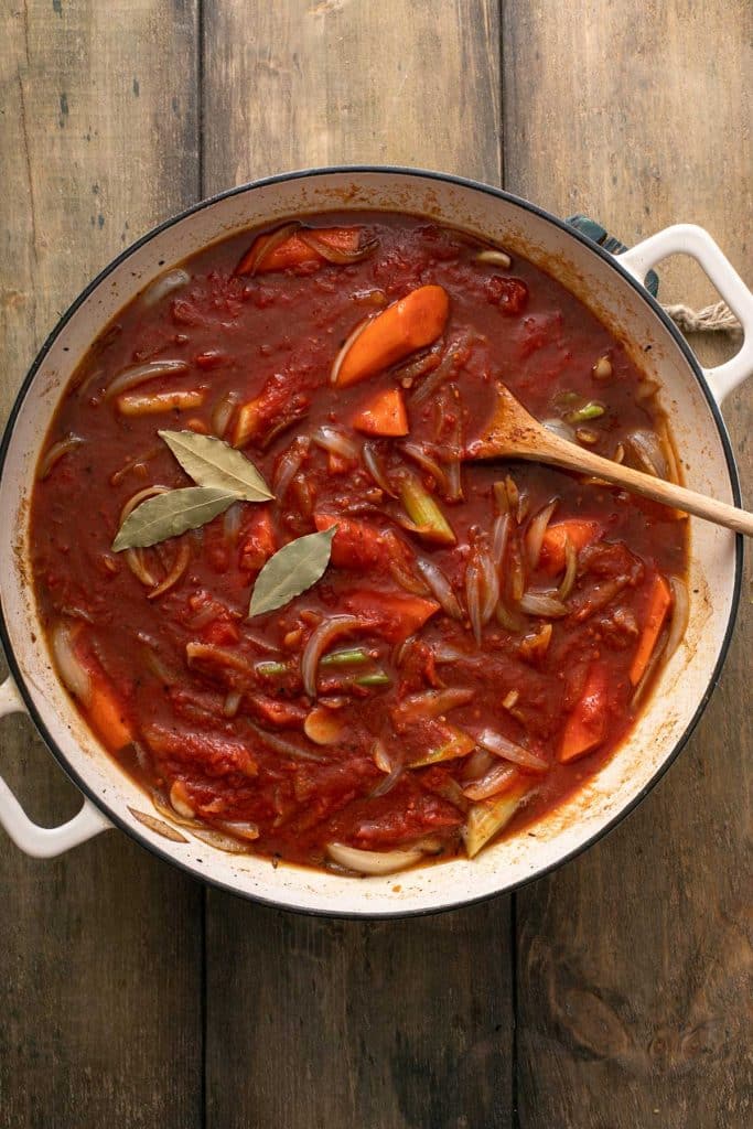 crushed tomatoes, broth, bay leaves and veggies simmering in a dutch oven