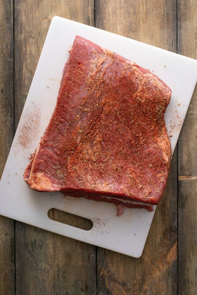 Seasoned raw meat on a white cutting board.