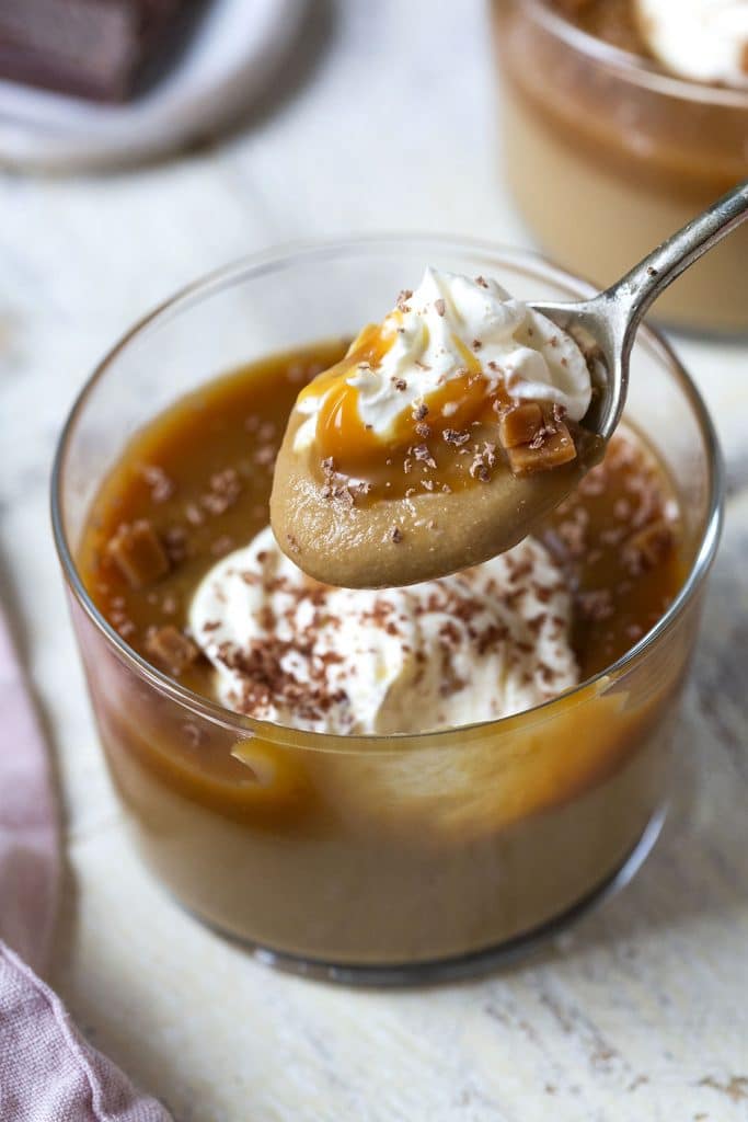Scooping creamy Butterscotch Pudding out of a small glass. 