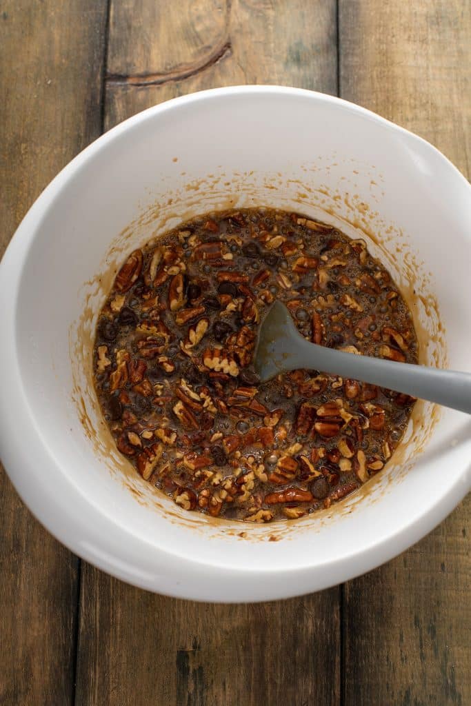 Chocolate pecan pie filling mixed in a large white bowl.