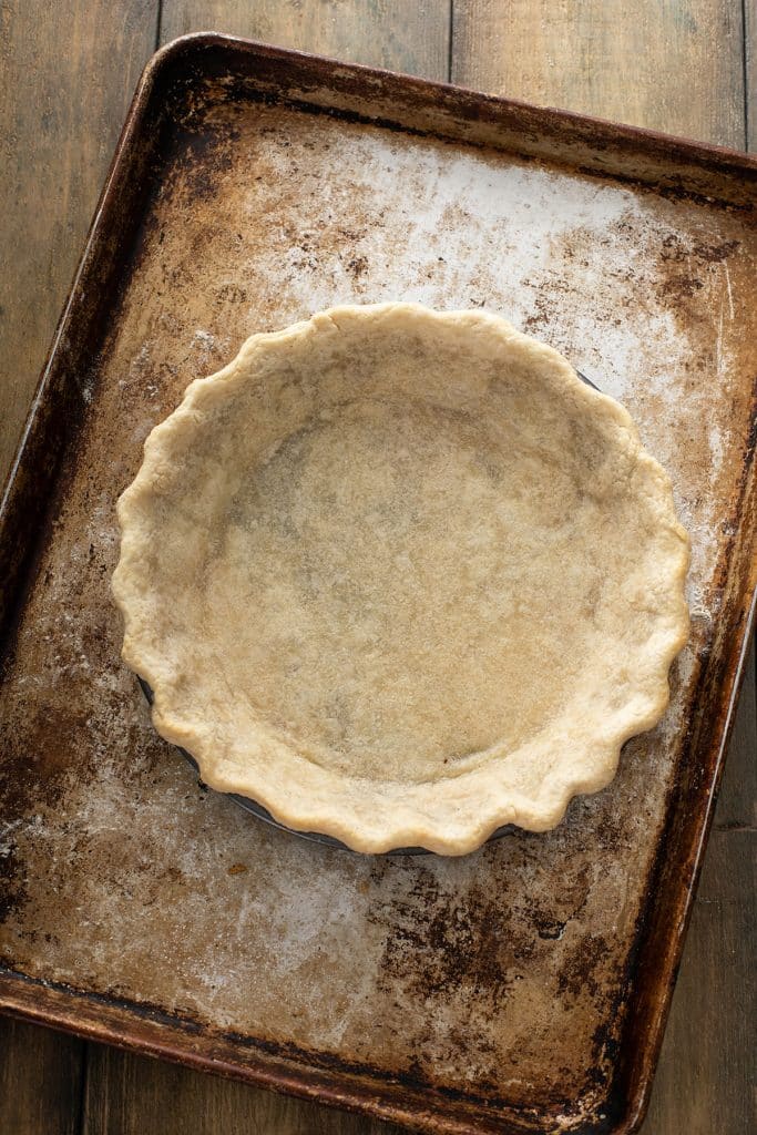 Baked pie crust in a pie dish over a baking tray
