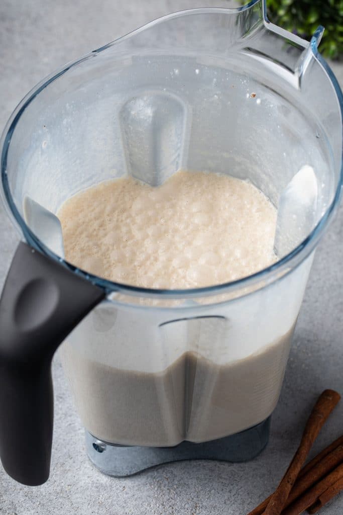 Blended coconut coquito drink in a blender glass