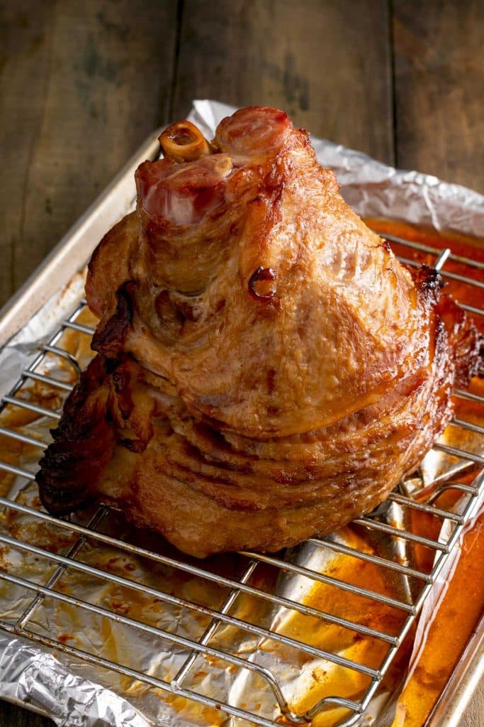 caramelized baked spiral ham on a baking sheet with a wire rack insert