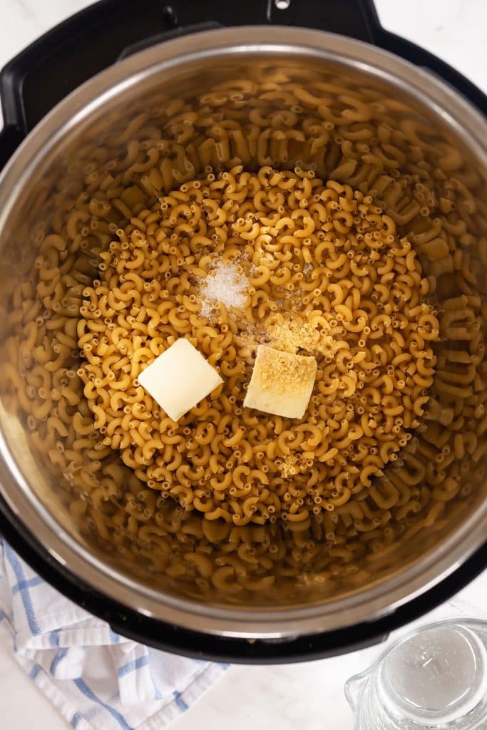 uncooked macaroni pasta, butter, garlic powder and salt in an instant pot  