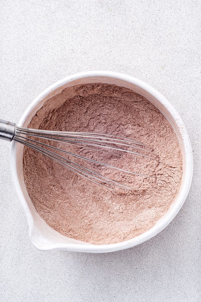 flour, baking powder, salt and cocoa powder into a white bowl with a whisk.