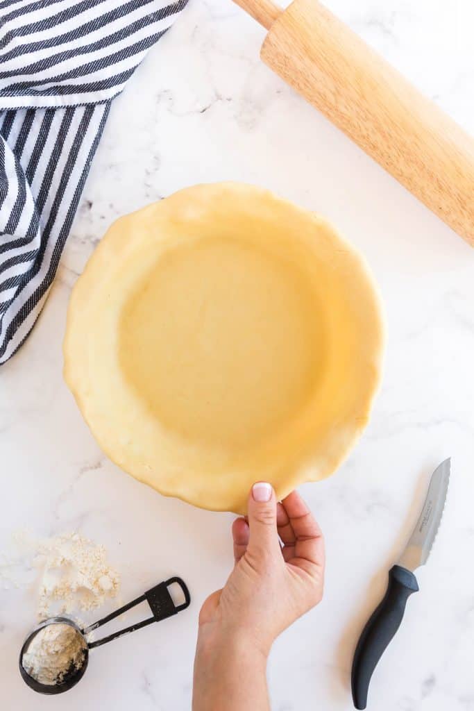 pinching the sides of dough of the pie dish 