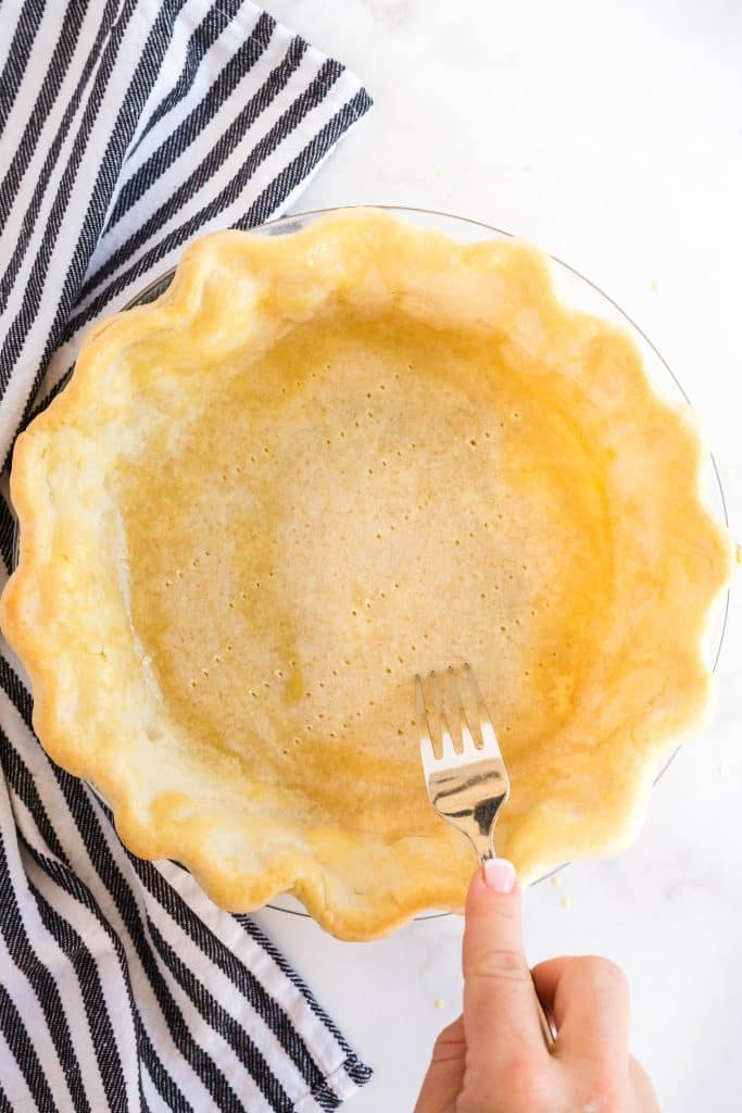 Pricking the bottom of a pie crust with a fork.
