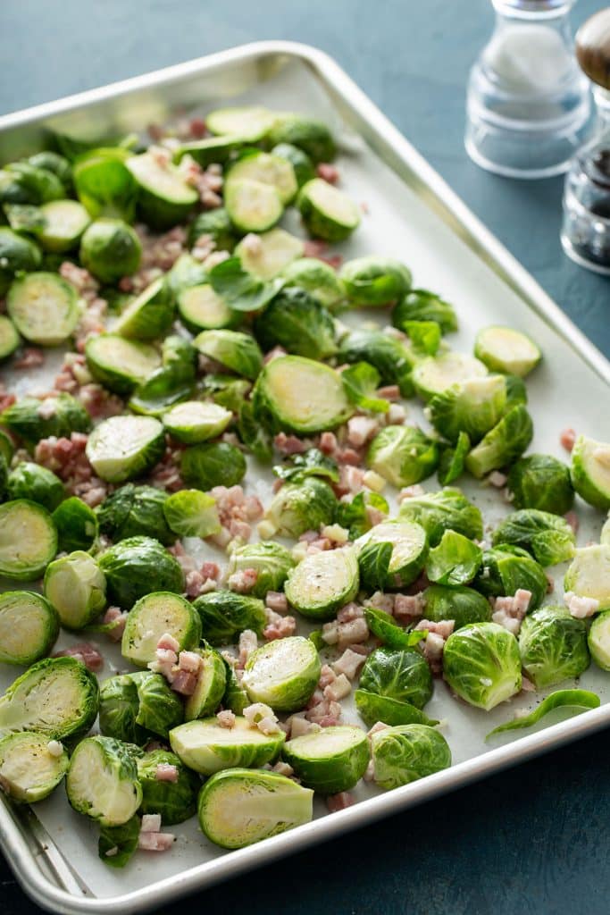 Brussels sprouts and chopped pancetta on a sheet pan.