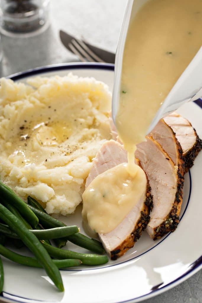 Turkey gravy is poured over slices of roasted turkey