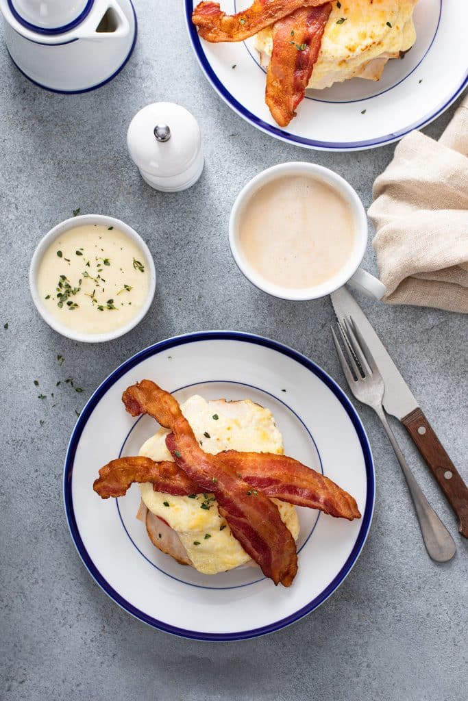 Hot brown sandwich topped with crispy bacon on a plate.