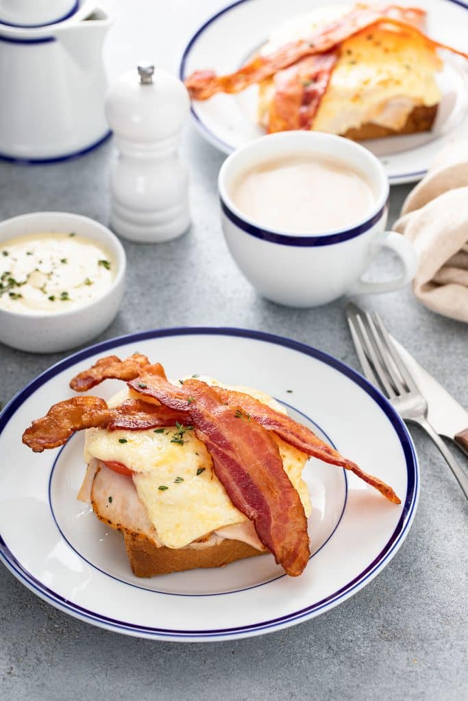 Toasty turkey sandwich with tomato crispy bacon and cheese sauce on a plate