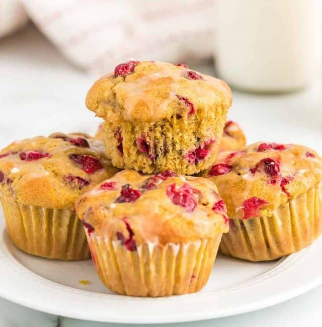 five cranberry orange muffins on a white plate