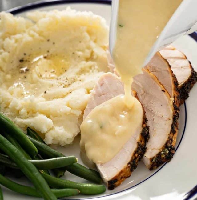 Turkey gravy is poured over slices of roasted turkey