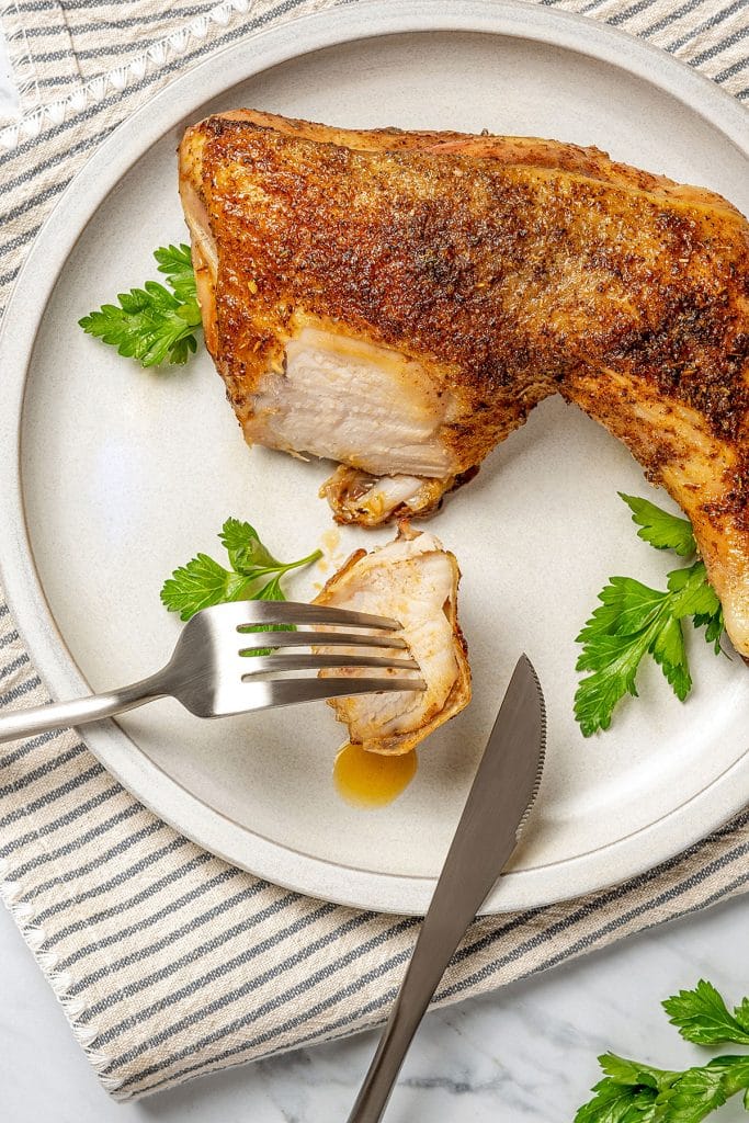 cutting a piece of a chicken leg quarter showing it's cooked to tender perfection.