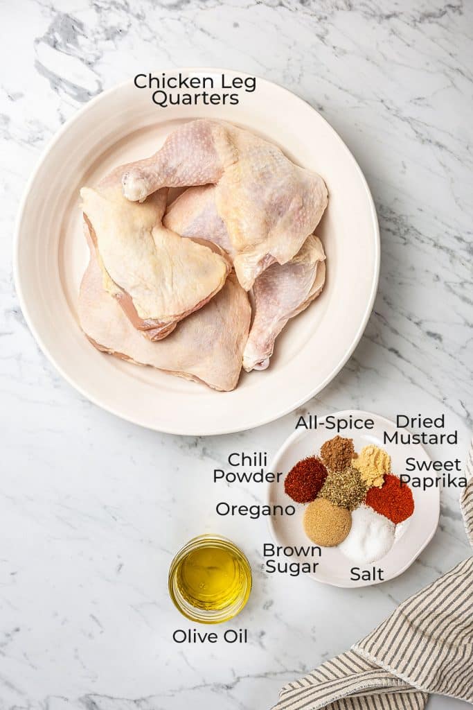 ingredients to make baked chicken leg quarters over a marble surface