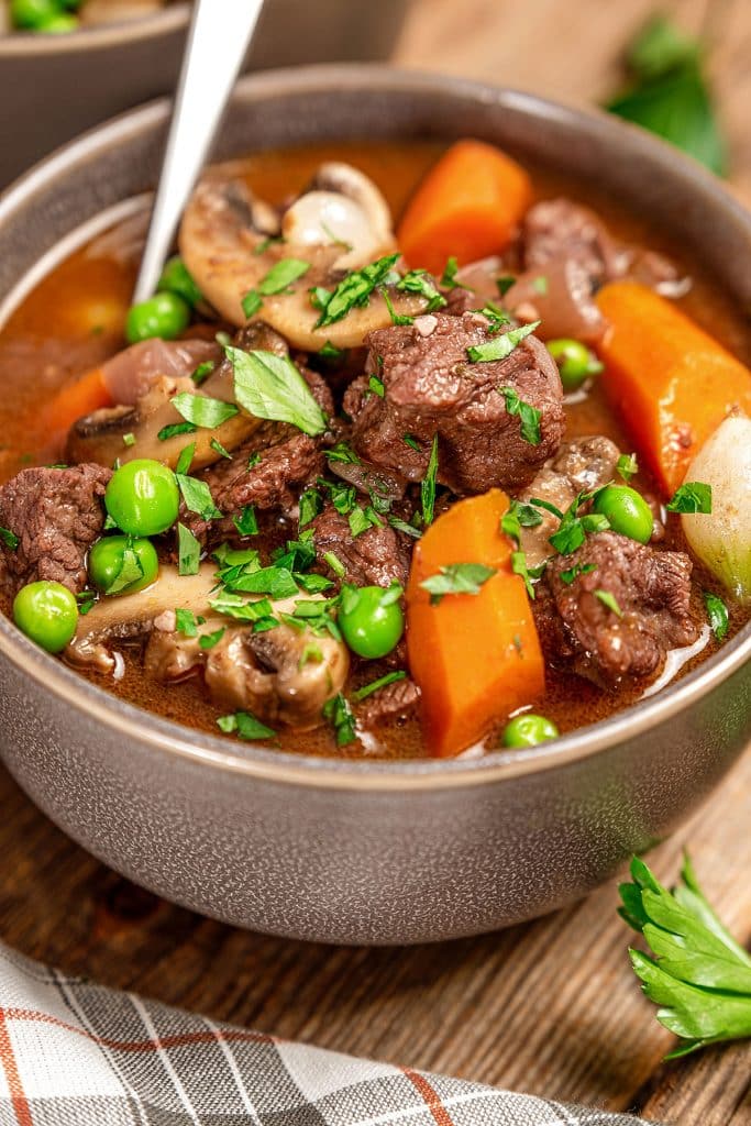 Beef stew with carrots, pearl onions, mushrooms and mushrooms in gravy served in a bowl.