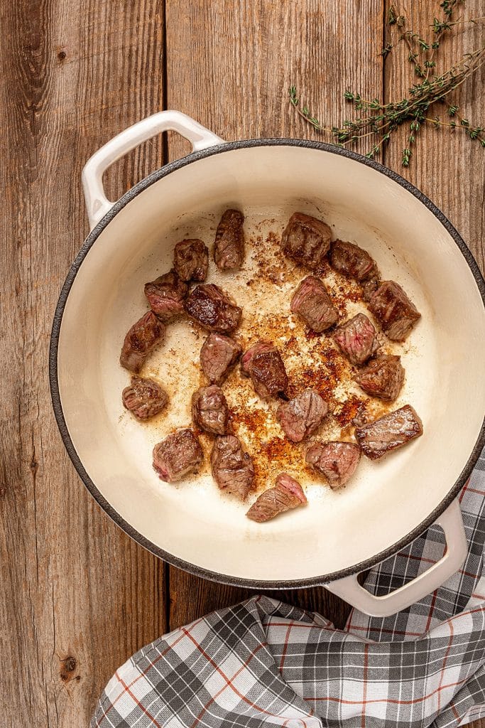 Golden brown beef stew meat chunks in a Dutch oven.