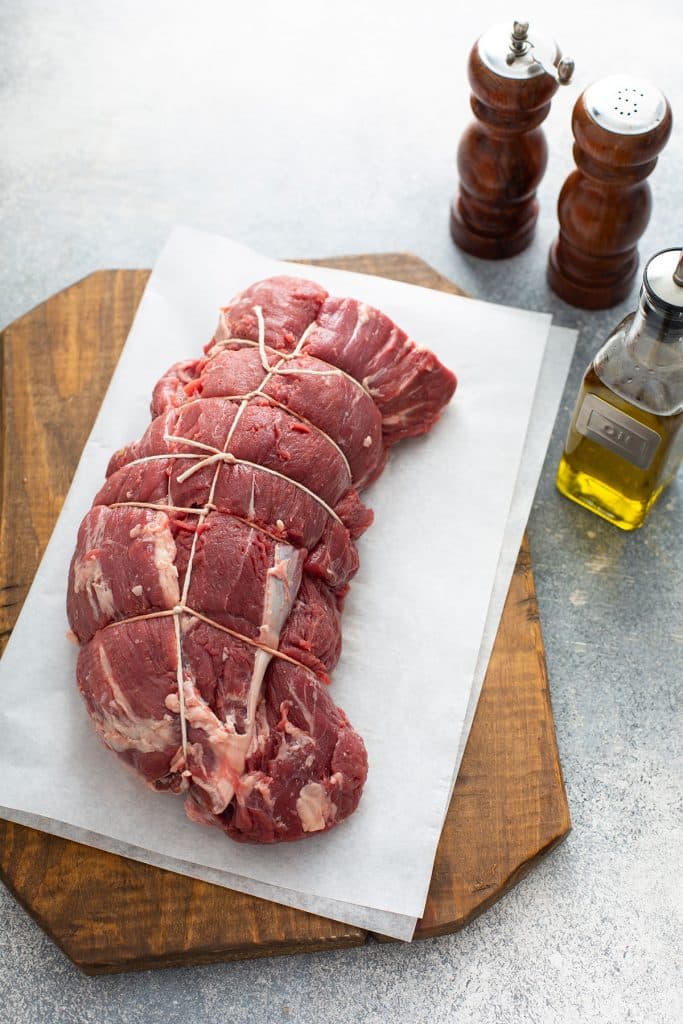 A trimmed and tied raw piece of beef tenderloin.