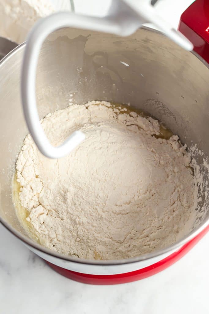 milk, water, eggs, sugar, salt and some of the flour in the bowl of a stand mixer.