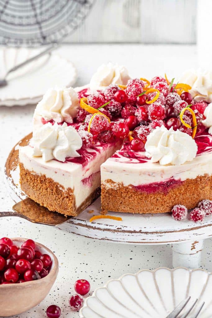Serving a slice of creamy cranberry cheesecake from a cake platter