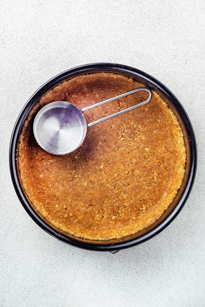 Pressing graham cookie crust into a springform pan