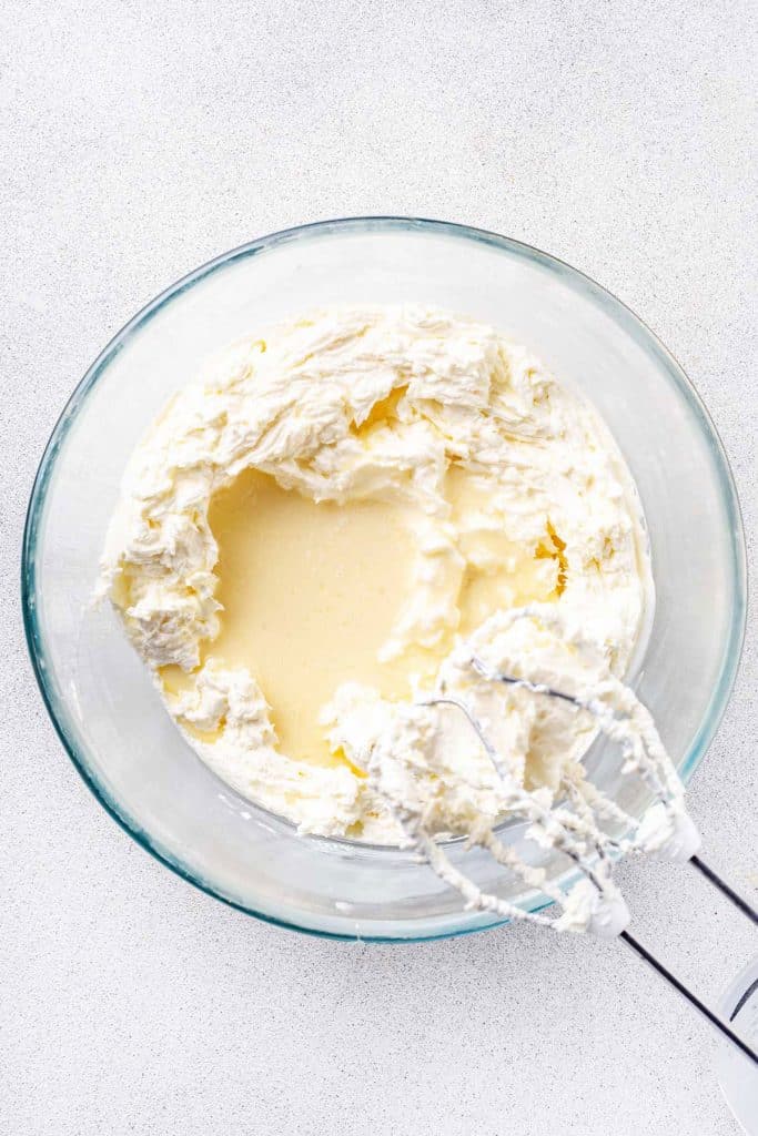Cream cheese and condensed milk in a mixing bowl