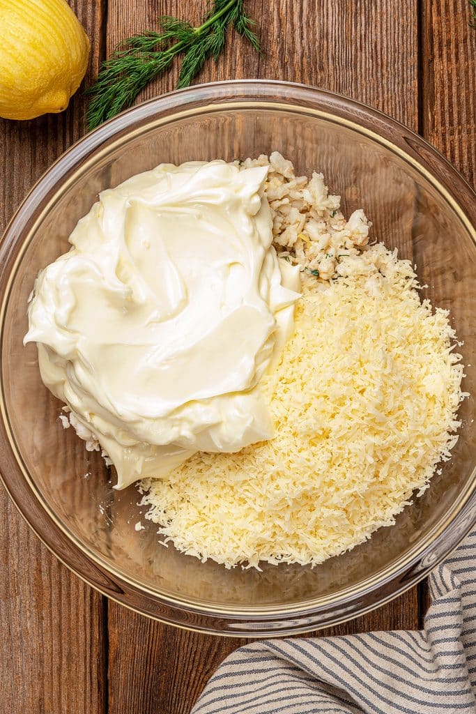 Crab meat, mayonnaise and shredded cheese in a large mixing bowl.