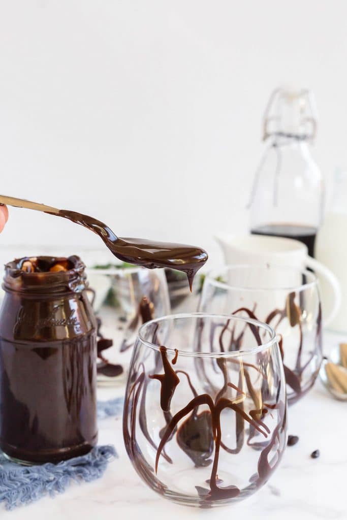 drizzling chocolate in a glass with a spoon.