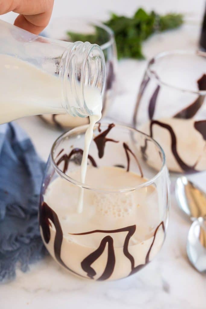 pouring milk to a Chocolate drizzled glass with kahlua and condensed milk.