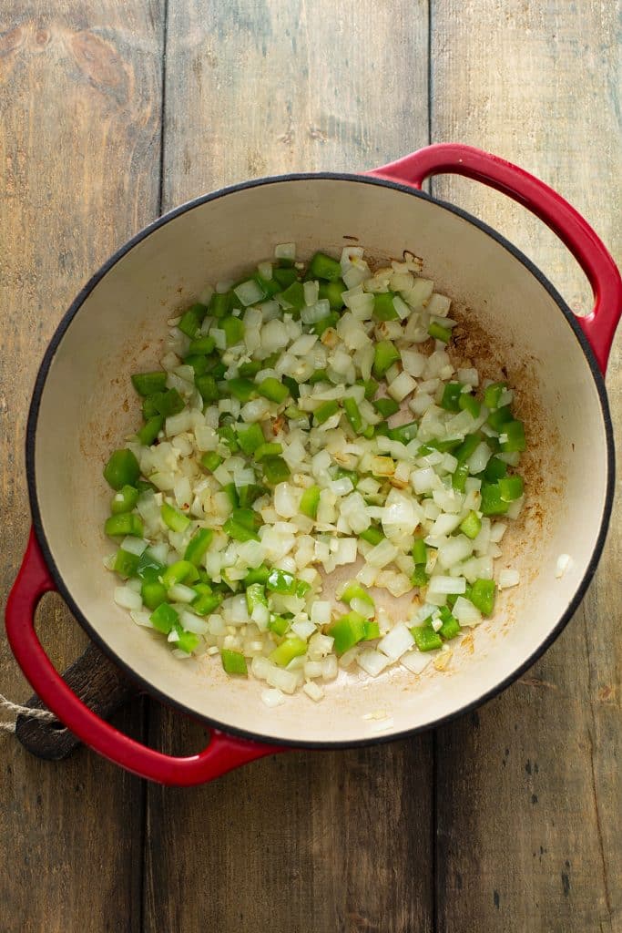 cooking onion and green bell pepper in a dutch oven
