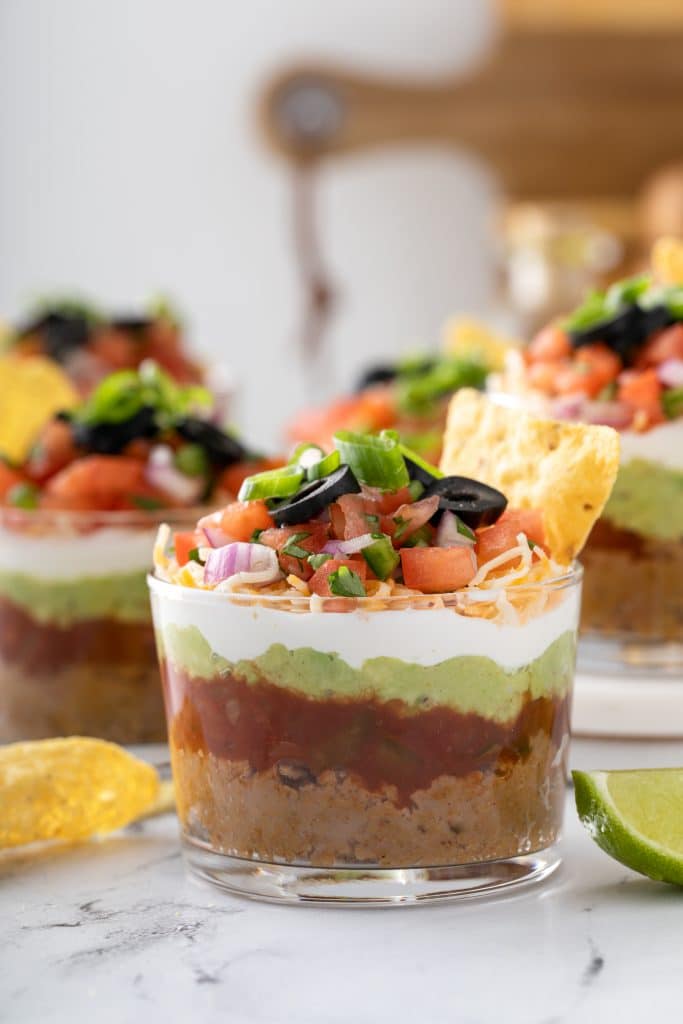 Seven layer dip served in a clear plastic cup.