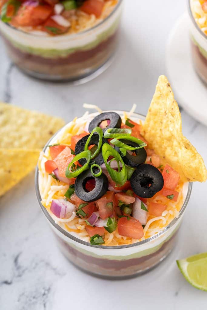Top view of 7-layer dip topped with pico de gallo and black olives.