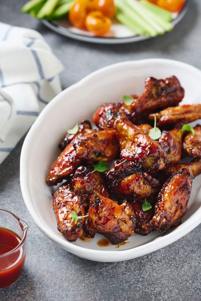 top view of air fryer chicken wings with bbq sauce in a white dish 