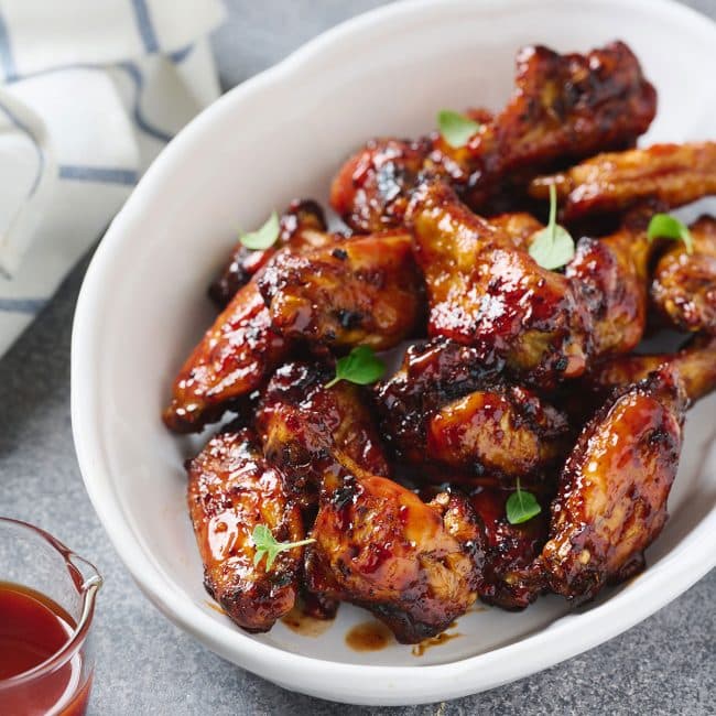 top view of air fryer chicken wings with bbq sauce in a white dish